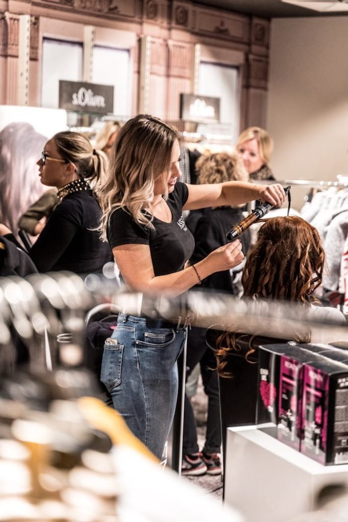 A skilled hairstylist uses a curling iron to style a clients hair in a busy salon.