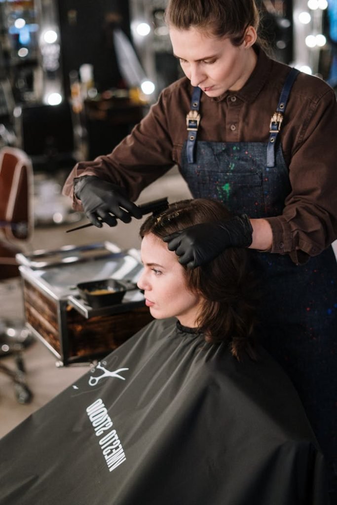 A hair stylist coloring a womans hair in a salon. Professional hairdressing in action.