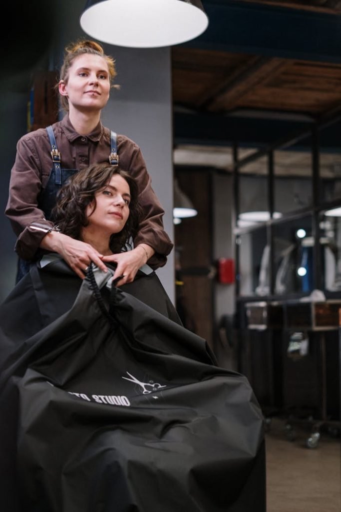 A stylist prepares a clients hair in a modern salon setting, showcasing the art of professional hairstyling.
